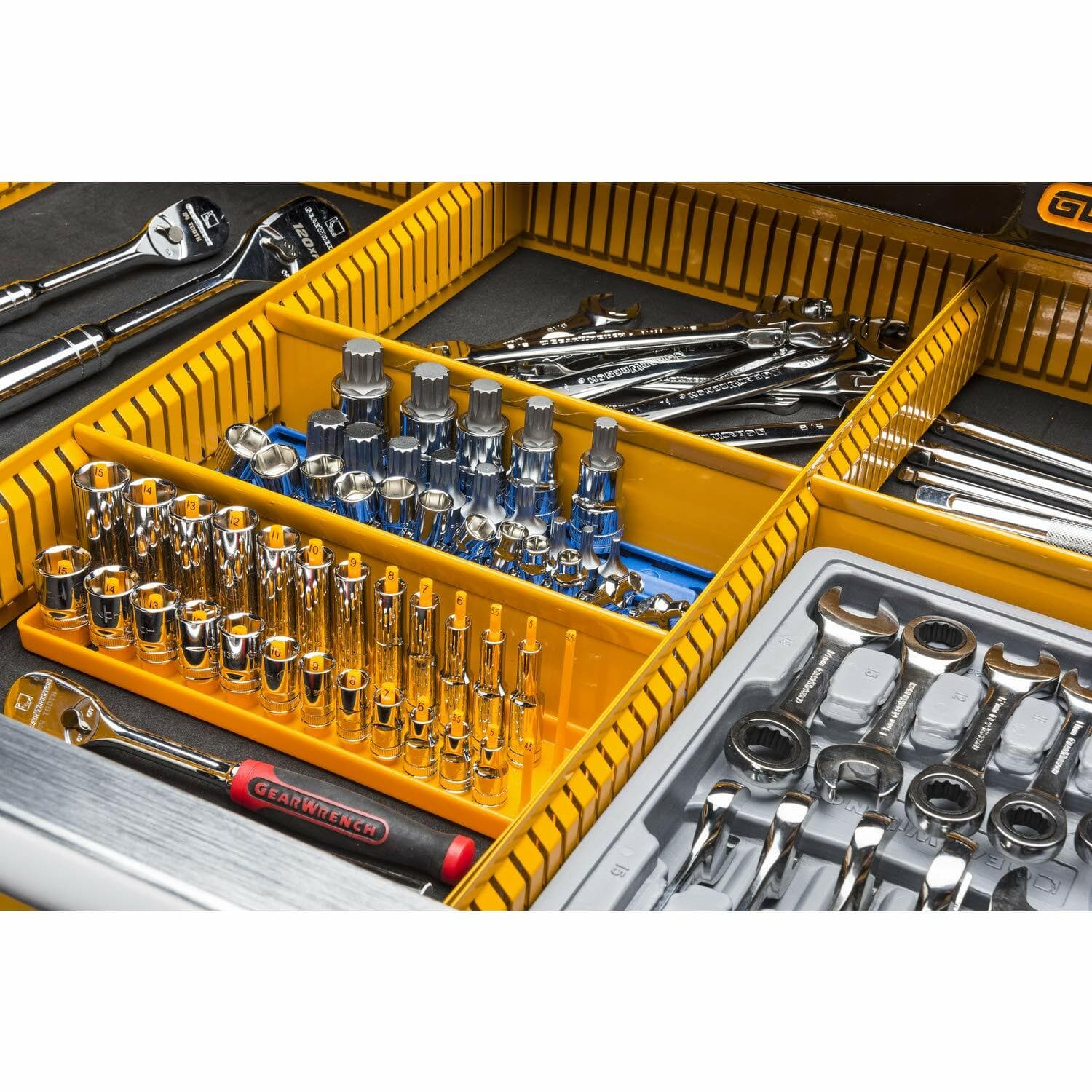 A close-up view of a drawer interior, showing tools organized within the yellow customizable partition system, including sockets, ratchets, and wrenches.