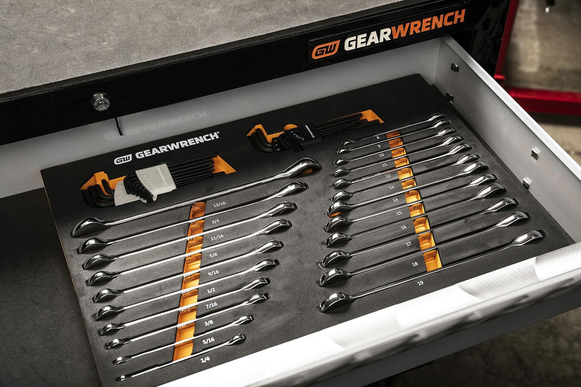 Open drawer of a GEARWRENCH tool chest showing a foam tray with combination wrenches and hex key sets. Wrenches range from 1/4" to 1", and hex keys are stored in orange and black holders. Each tool is labeled and securely organized.