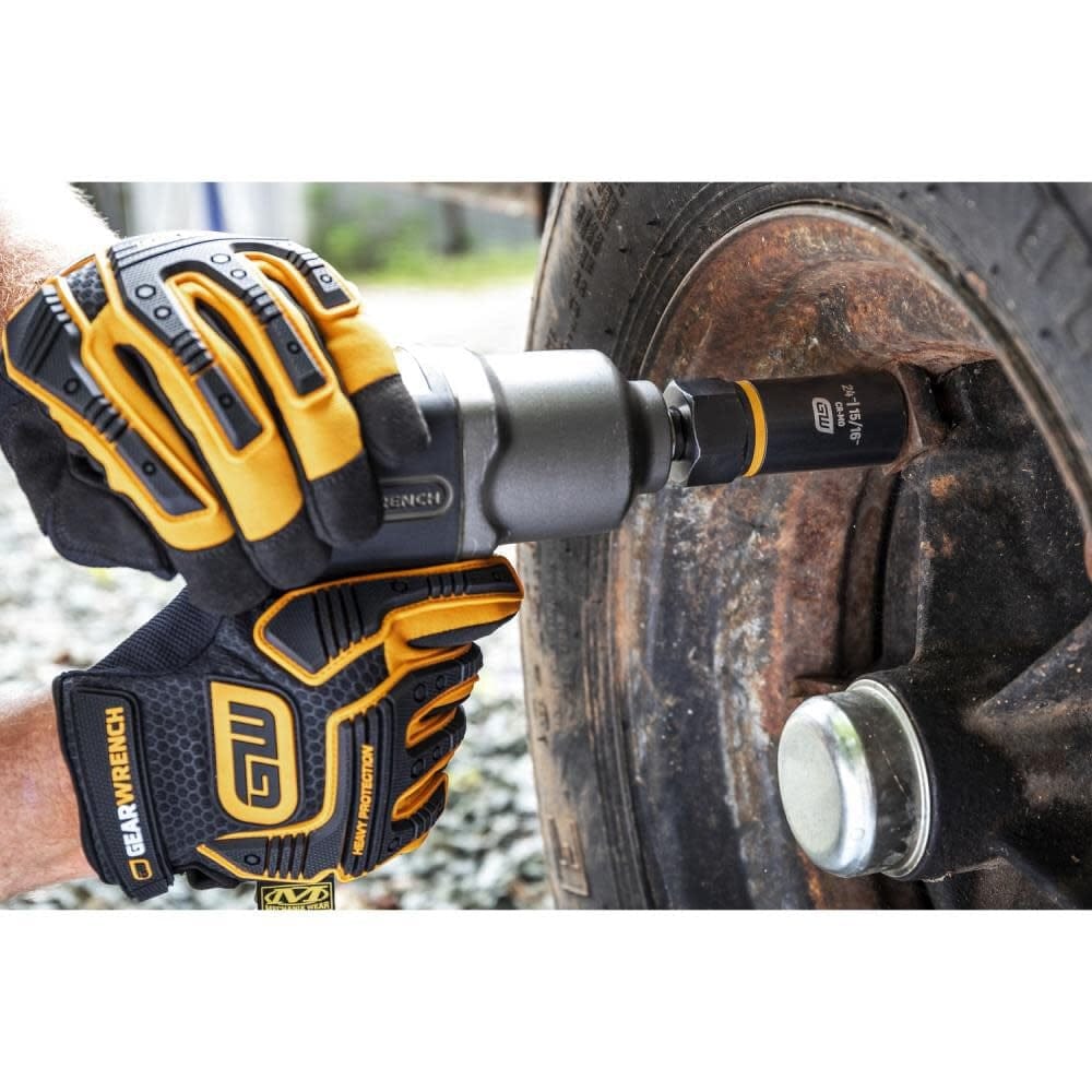 A mechanic wearing black and yellow protective gloves using an air impact gun with a GEARWRENCH Bolt Biter socket to remove a lug nut from a severely rusted wheel.