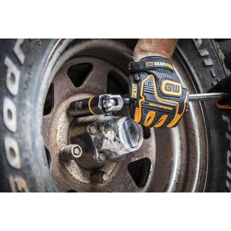 A close-up of a mechanic using a hand ratchet with a GEARWRENCH Bolt Biter extraction socket attached to work on a rusted lug nut on an old vehicle wheel.