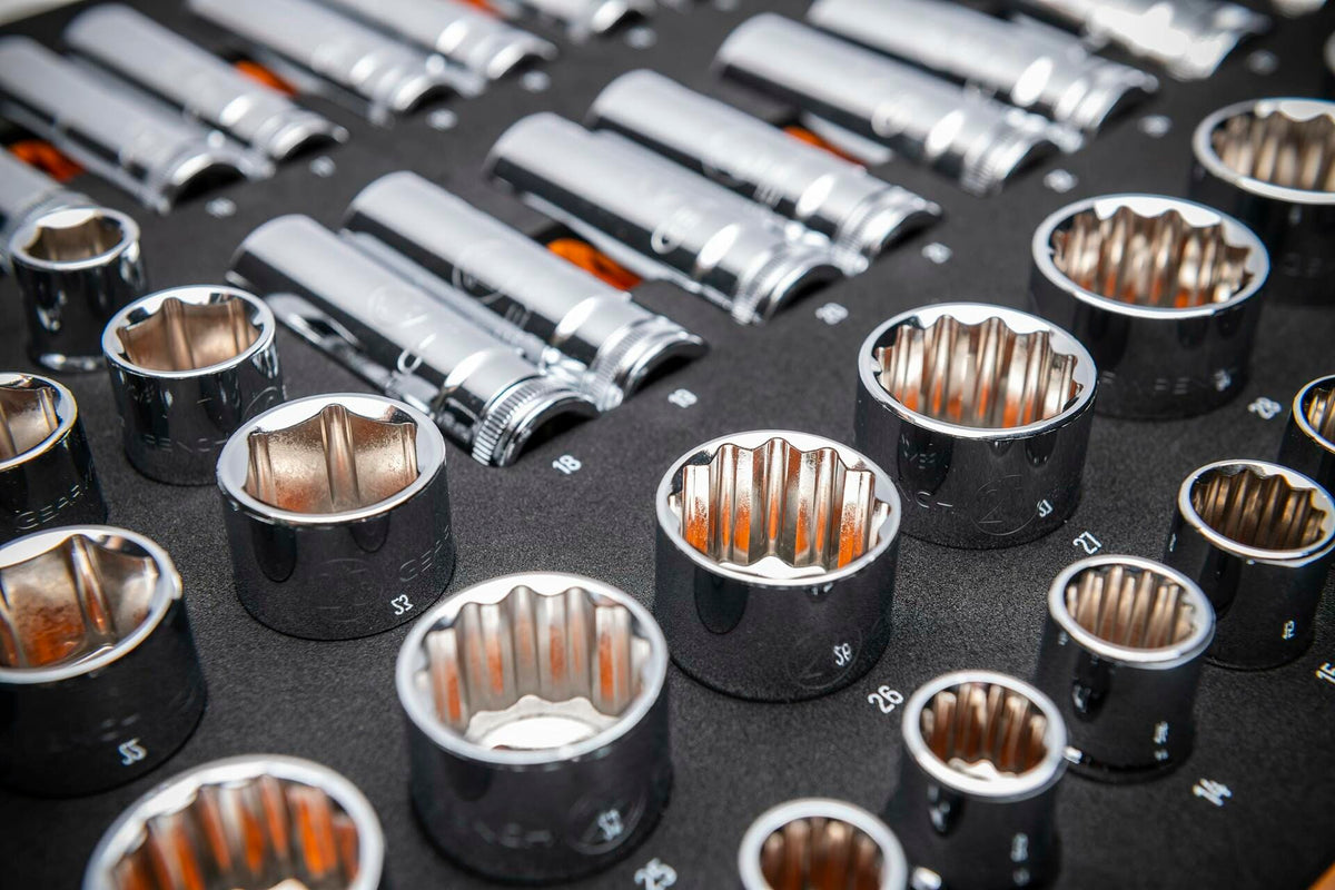 Chrome 12-point metric sockets arranged in rows on a black foam tray. Sizes range from 13mm to 26mm, with standard sockets in front and deep sockets in back. Each socket is labeled and organized for professional use.