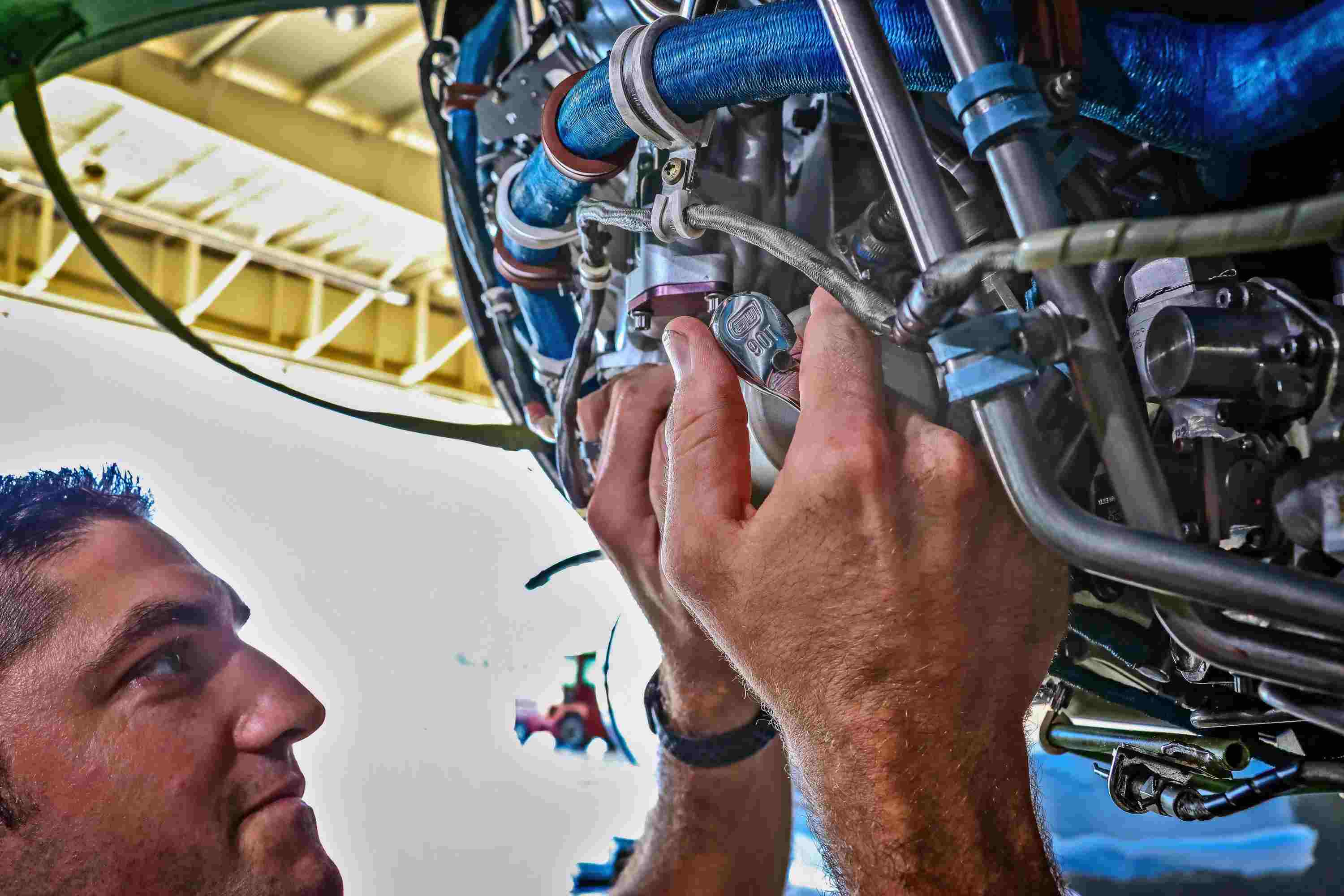 A professional technician using a GEARWRENCH 90-tooth ratchet to work on a complex industrial engine assembly, demonstrating the tool's precision and ease of use in confined spaces.
