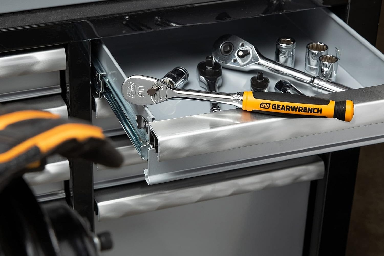 A lifestyle shot of the GEARWRENCH 81208T professional ratchet sitting in a tool chest drawer alongside various sockets, highlighting its high-visibility handle and organized workshop utility.