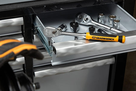 A lifestyle shot of the GEARWRENCH 81208T professional ratchet sitting in a tool chest drawer alongside various sockets, highlighting its high-visibility handle and organized workshop utility.