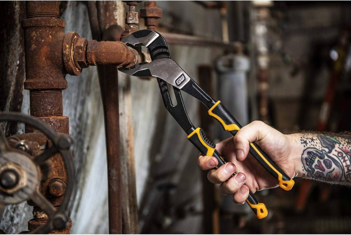 An industrial technician using the GEARWRENCH 82168C PITBULL V-Jaw pliers to loosen a rusted heavy-duty pipe fitting in a professional maintenance environment.