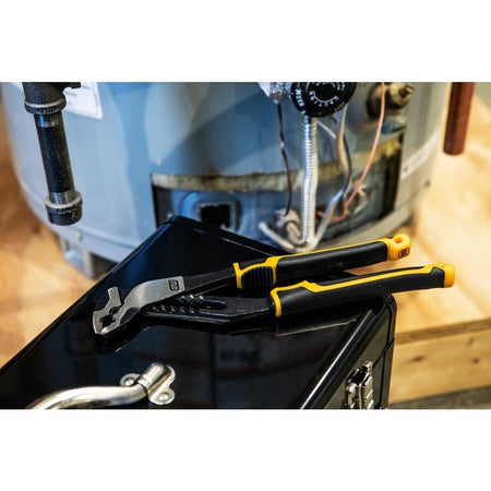 GEARWRENCH 82168C tongue and groove pliers resting on a black tool chest in front of a residential water heater, illustrating its portability and readiness for professional plumbing repairs.