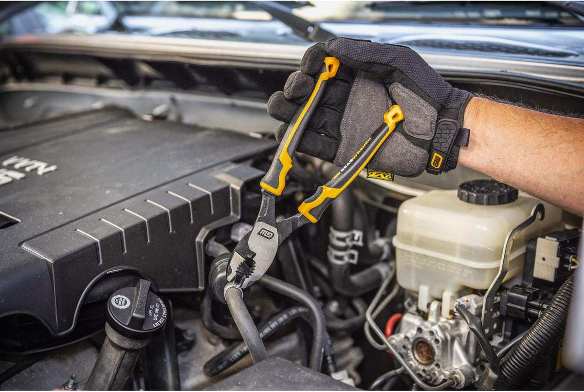Automotive mechanic wearing work gloves using the high leverage GEARWRENCH PITBULL slip joint pliers to securely adjust a hose clamp inside a vehicle engine bay.