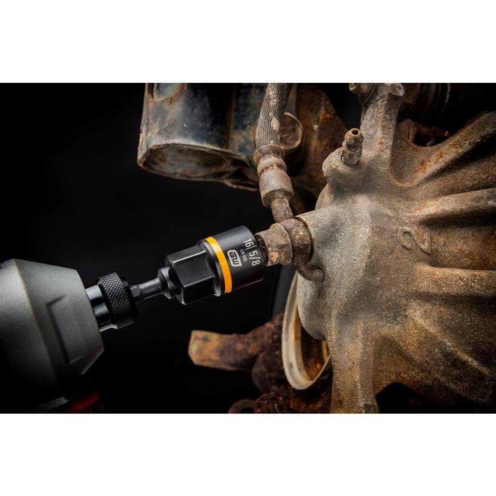 Action shot demonstrating a GEARWRENCH Bolt Biter extraction socket attached to a power impact driver, successfully loosening a severely rusted and damaged automotive suspension fastener.