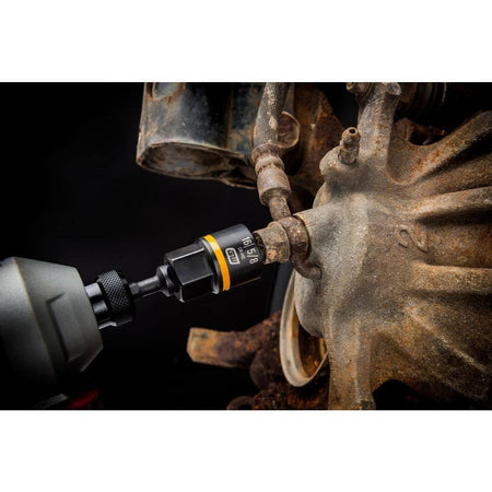 Action shot demonstrating a GEARWRENCH Bolt Biter extraction socket attached to a power impact driver, successfully loosening a severely rusted and damaged automotive suspension fastener.