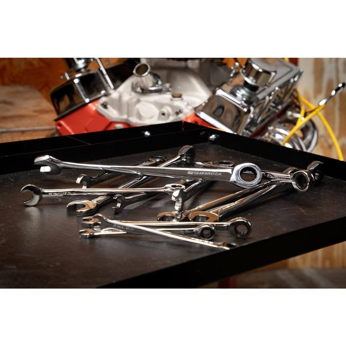 A variety of GEARWRENCH XL X-Beam wrenches scattered on a work surface in a professional shop, illustrating the diverse metric sizes available in this high-torque combination kit.