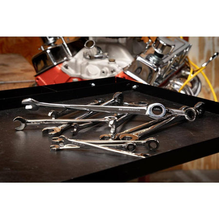 A variety of GEARWRENCH XL X-Beam wrenches scattered on a work surface in a professional shop, illustrating the diverse metric sizes available in this high-torque combination kit.