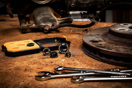 A lifestyle shot of the GEARWRENCH Bolt Biter wrench inserts and storage case on a professional workbench next to industrial tools, showcasing their rugged alloy steel construction and manganese phosphate finish.