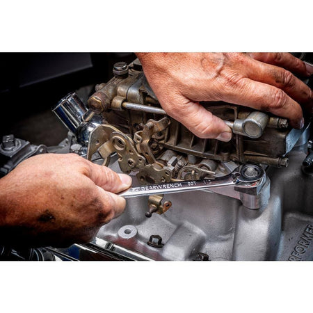 An action photo of a technician using a GEARWRENCH 1/2 inch 90-tooth ratcheting wrench to adjust a fastener on a complex engine assembly, demonstrating the tool's low-profile access and professional utility.