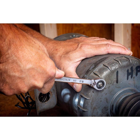 A professional using the GEARWRENCH 7/16 inch ratcheting wrench to tighten a bolt on an industrial electric motor, showcasing the 12-point box end's secure grip and the tool's long beam leverage.