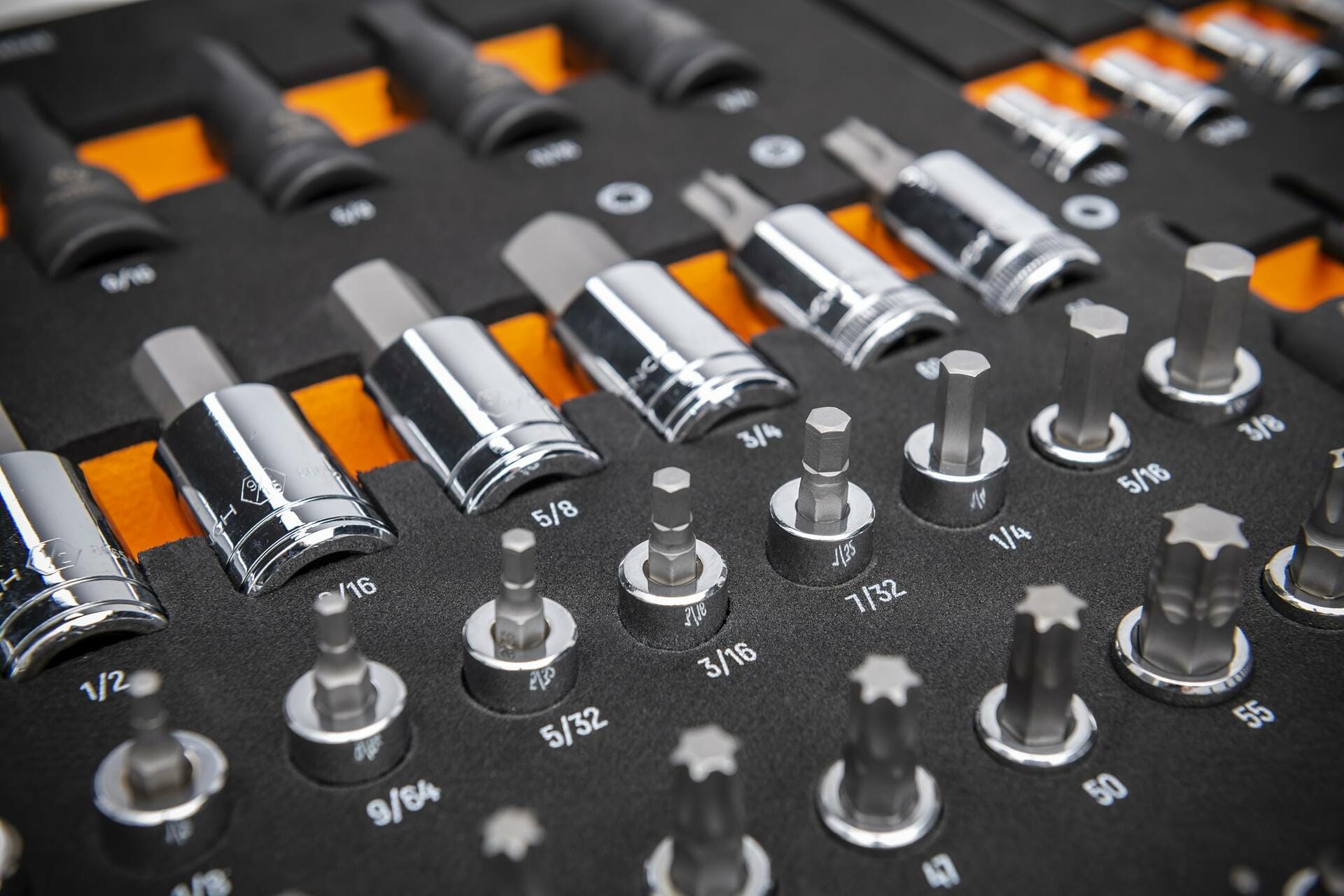 Chrome-finished SAE socket bits arranged in rows on a labeled tray; includes hex, Torx, and standard sockets ranging from 5/32 to 9/16 inches for mechanical and automotive applications.