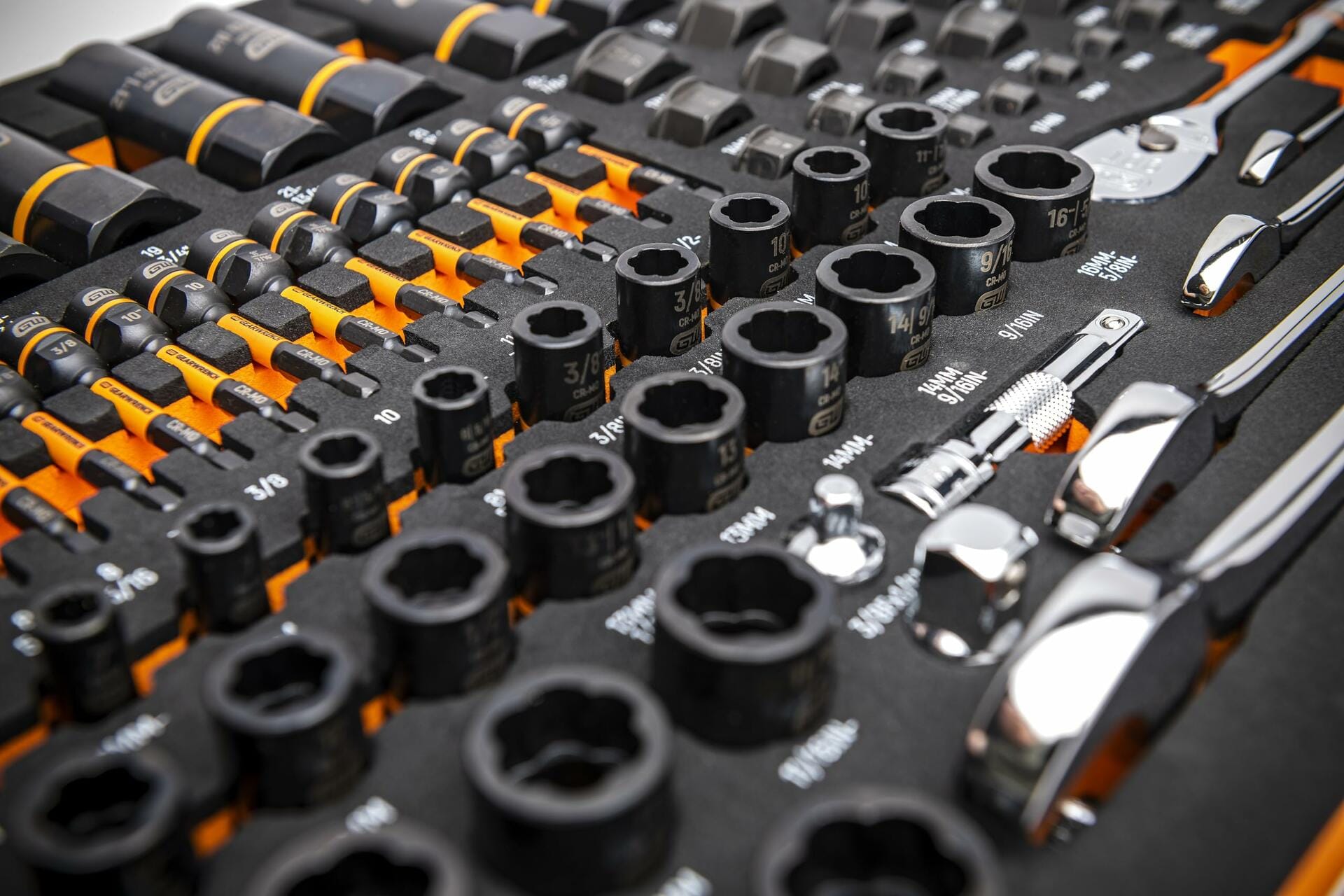 GEARWRENCH socket and ratchet set in labeled foam tray with metric and SAE sizes; includes chrome-finished ratchets, extensions, and screwdrivers with black and orange handles.