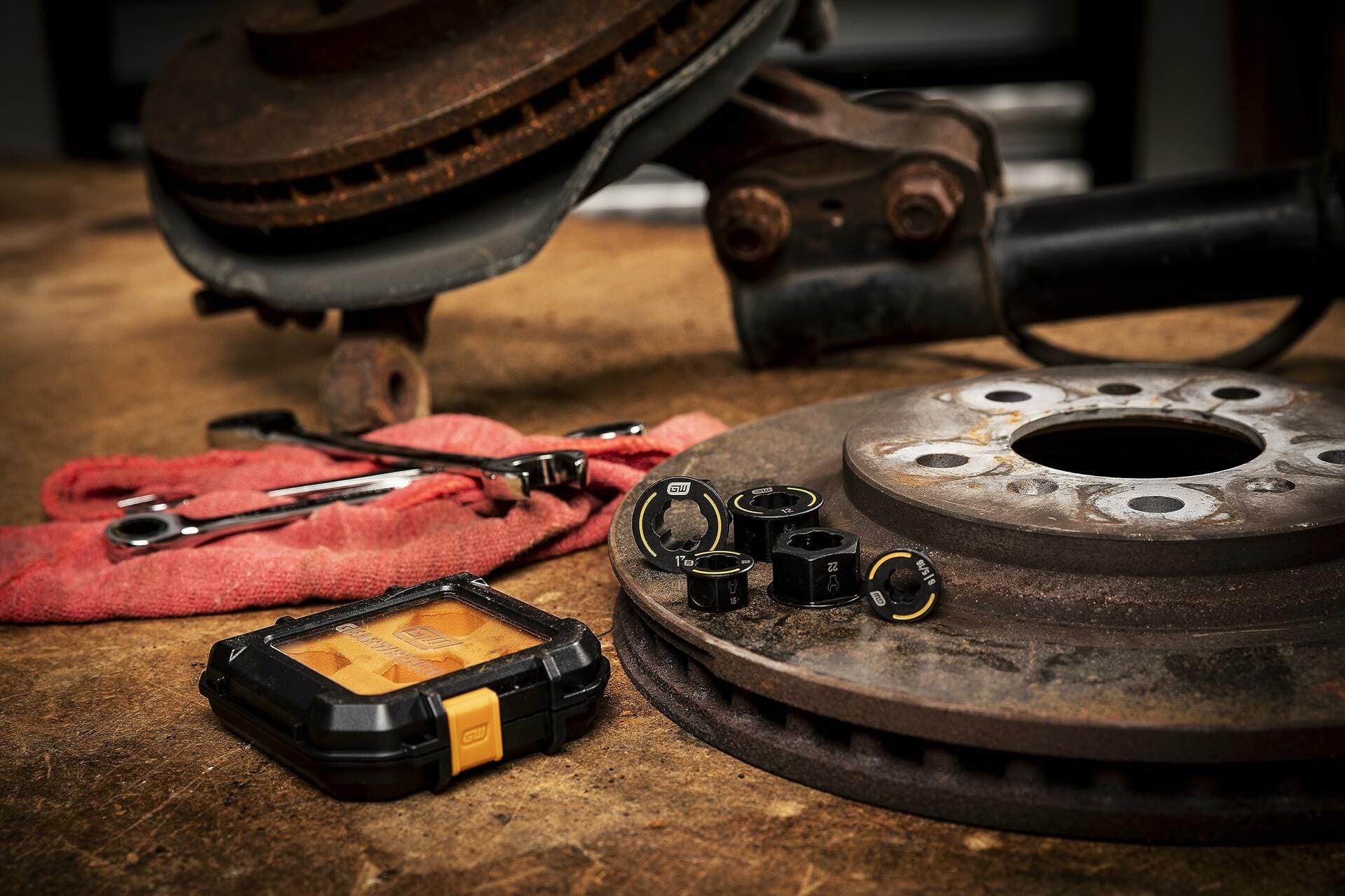 The 5-piece Bolt Biter insert set and its case displayed on a workbench next to a rusty brake rotor and other tools.