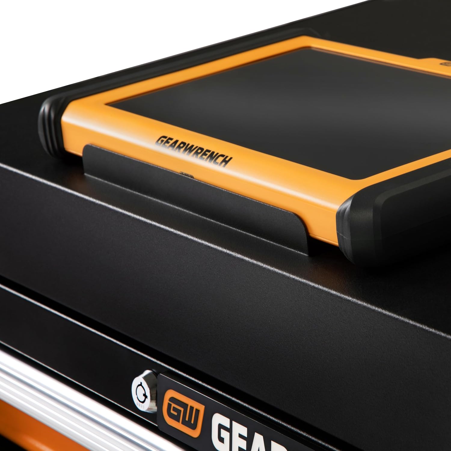A detail macro shot showcasing an orange and black GEARWRENCH multi-system diagnostic scanning tablet seated flat inside the integrated steel top security rest plate situated directly above the keyed tubular cylinder drawer lock interface.