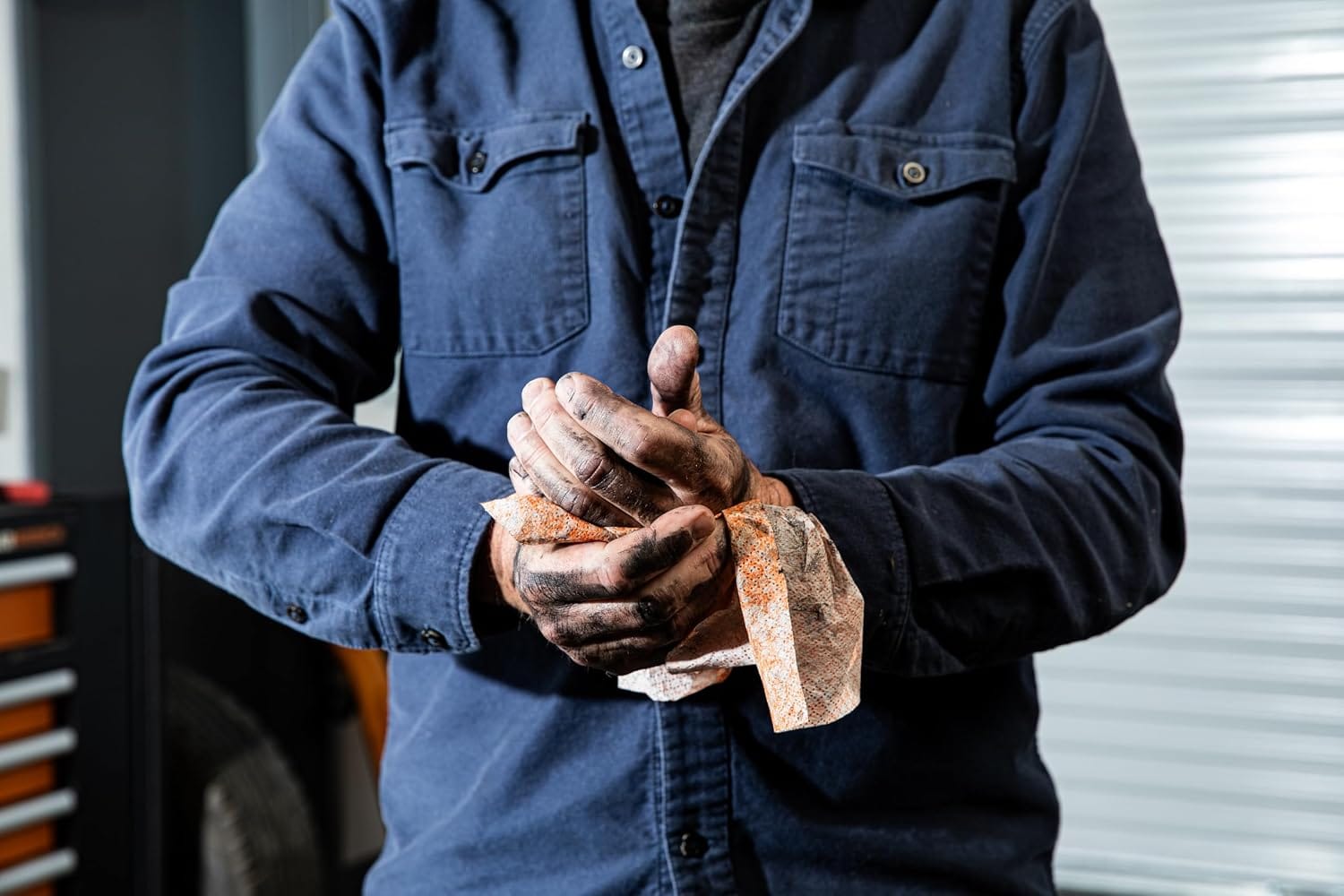A technician uses a solvent-free dual-textured wipe to break down grease and stubborn carbon grime on hands without skin irritation.
