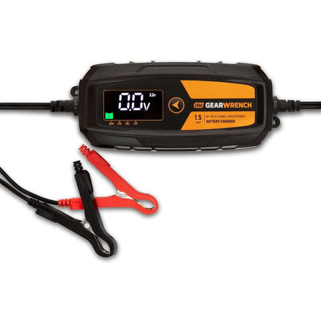 A studio product view of the GEARWRENCH 1.5A battery charger and maintainer. The image shows the main digital control unit with a black and molten orange housing, accompanied by the heavy-duty red and black battery terminal clamps.