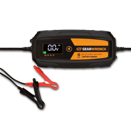 A studio product view of the GEARWRENCH GWBC100 10A battery charger and maintainer. The image shows the primary digital control unit with a black and molten orange housing, accompanied by heavy-duty red and black battery terminal clamps.