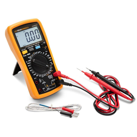 Angled view of the GEARWRENCH 1000V AC/DC tester GWDM107 standing upright using its built-in kickstand, positioned next to the included red and black test leads and thermocouple.