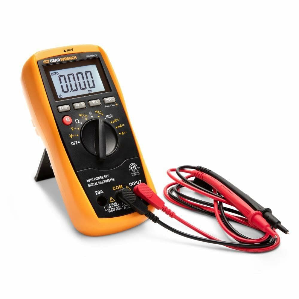 GEARWRENCH digital multimeter with orange casing and black front panel, showing 0.000 DC reading and connected probes, positioned on fold-out stand.