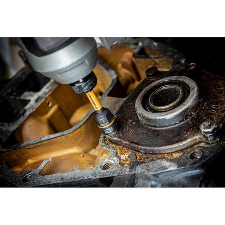 Cordless power tool with GearWrench bit engaging a fastener on a rusted metal housing near a bearing, illustrating mechanical disassembly in industrial repair work.
