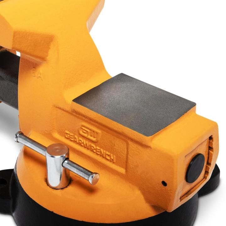 Side view of an orange GearWrench bench vise mounted on a black circular base, showing the embossed brand name and jaw assembly.
