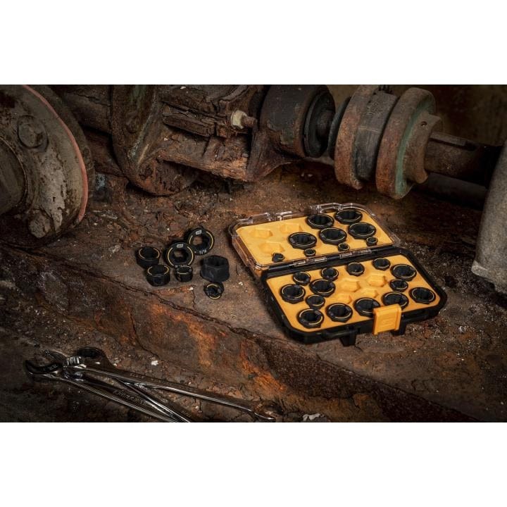 Open yellow GearWrench Bolt Biter case with black sockets scattered on a rusty workshop surface, surrounded by wrenches and industrial components.