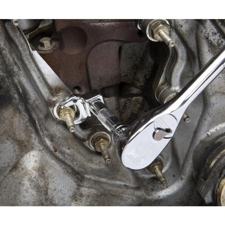 Close-up of a mechanic using a chrome GearWrench crowfoot wrench attached to an extension bar to loosen a nut in a crowded engine bay.