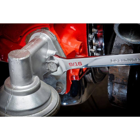 Close-up of a GearWrench 9/16 inch open end wrench loosening a silver bolt on a red engine component.