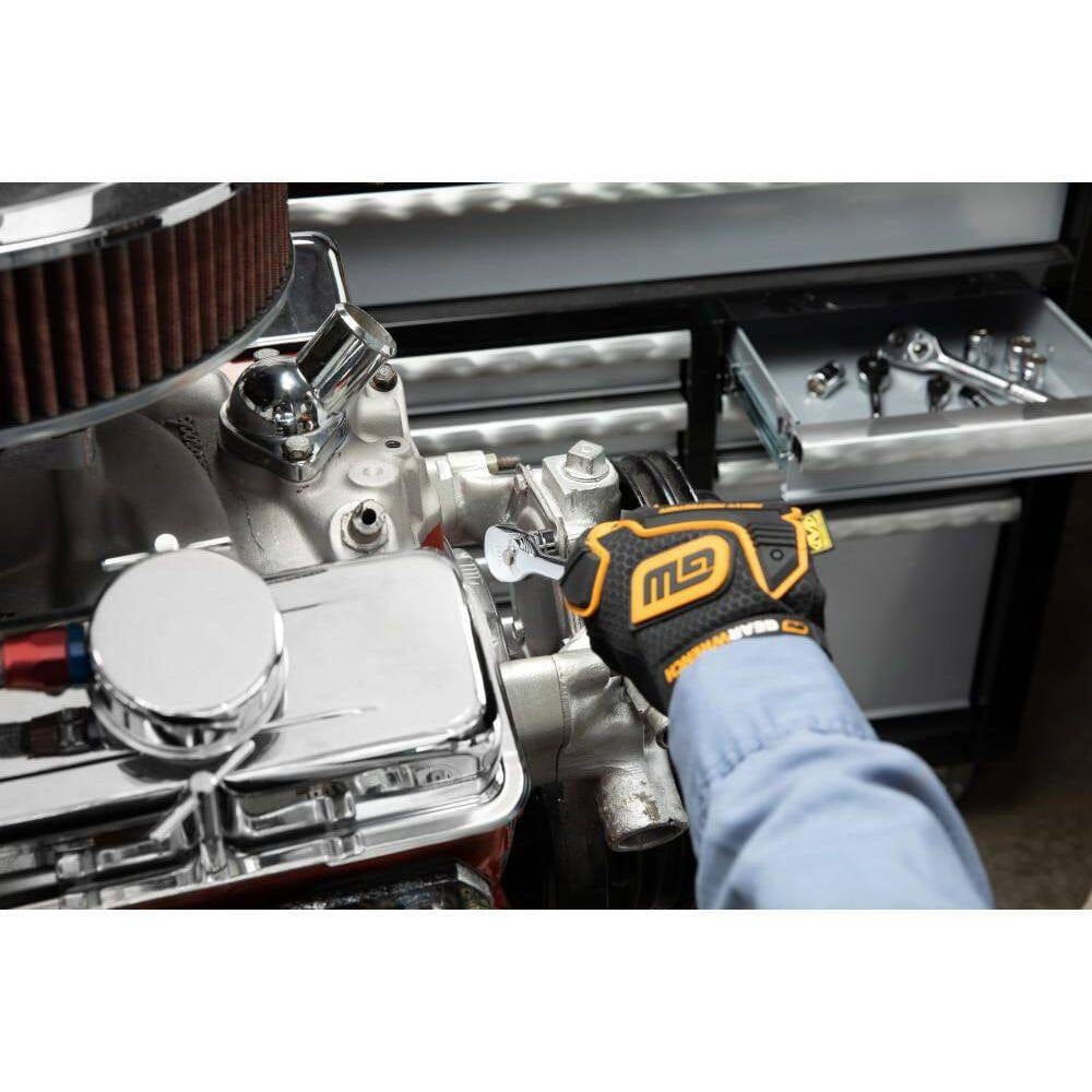 Mechanic wearing gloves uses a wrench on a chrome car engine near a drawer of organized hand tools.