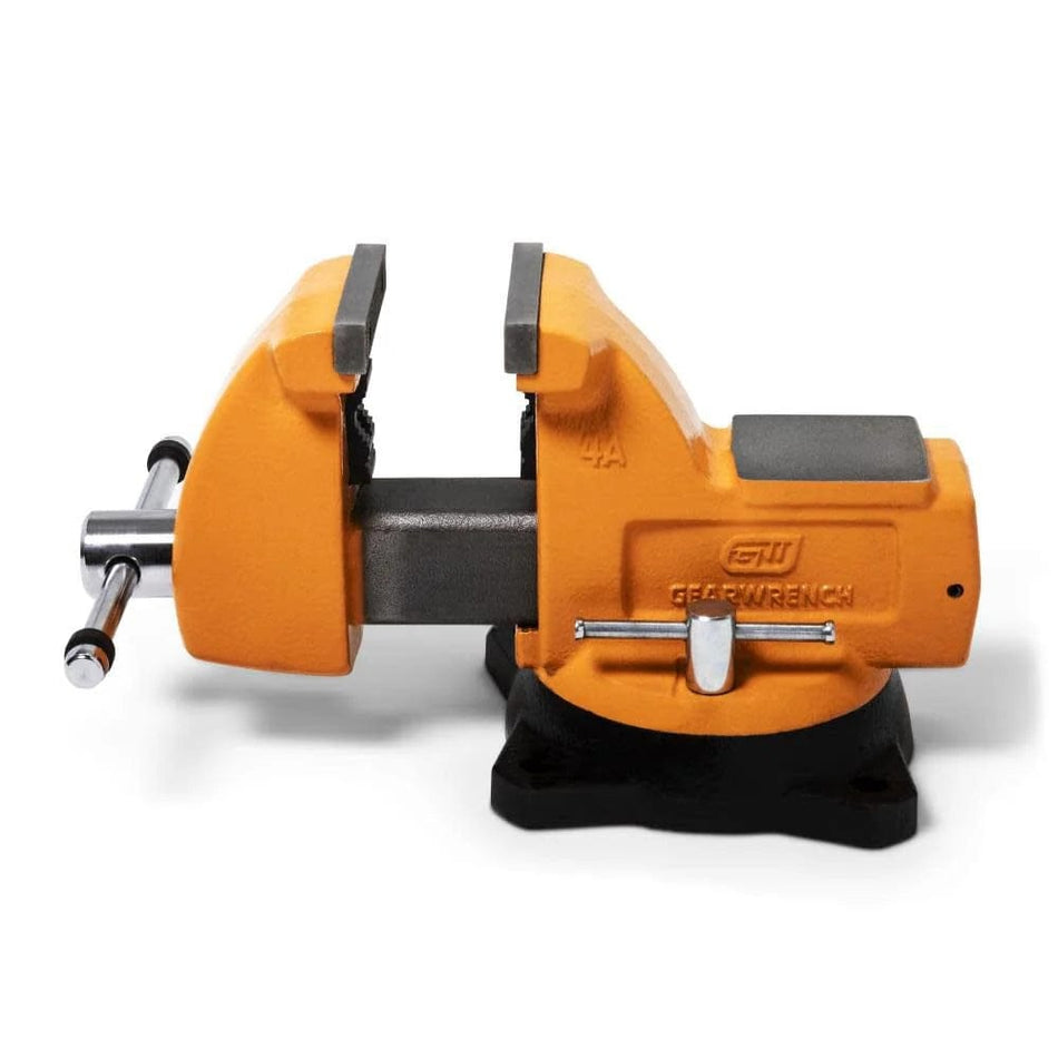 Orange GearWrench bench vise mounted on a workbench with rotating base, serrated jaws, and embossed branding, used for holding materials during mechanical work.