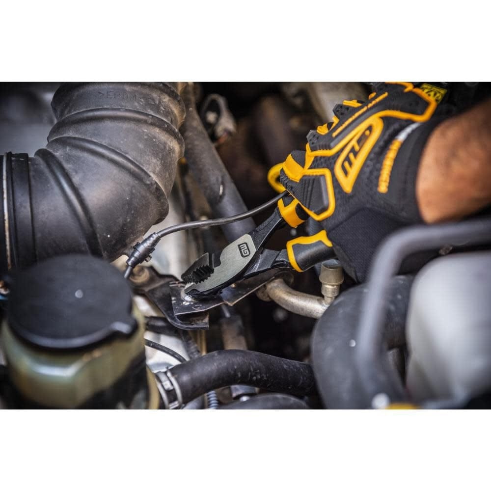 Mechanic wearing black and yellow gloves using GearWrench pliers to grip a component inside a car engine bay during automotive repair.