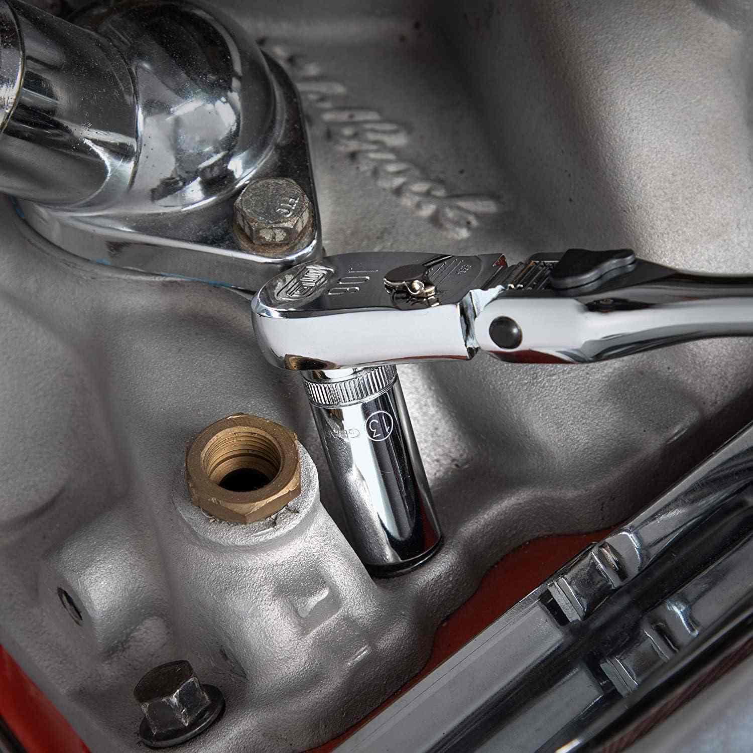 Action shot of a ratchet and socket with an extension bar tightening a bolt on a silver engine component.