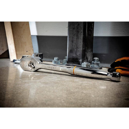 Torque wrench on a concrete floor near a bolted steel column base, with gloves and wood in a construction setting.