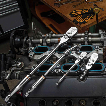All four GEARWRENCH 90-tooth flex-head ratchets from the set are displayed on top of a disassembled car engine.