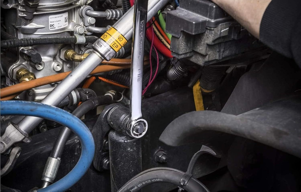 Action shot of the long pattern wrench being used to access a difficult bolt within a cluttered engine compartment.