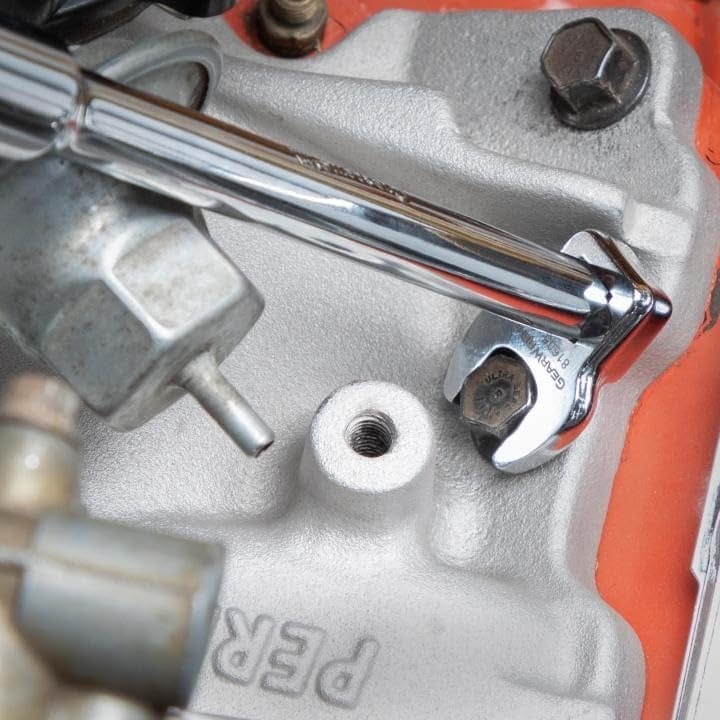 Close-up action shot of a crowfoot wrench attached to an extension bar tightening a bolt on a silver engine component.