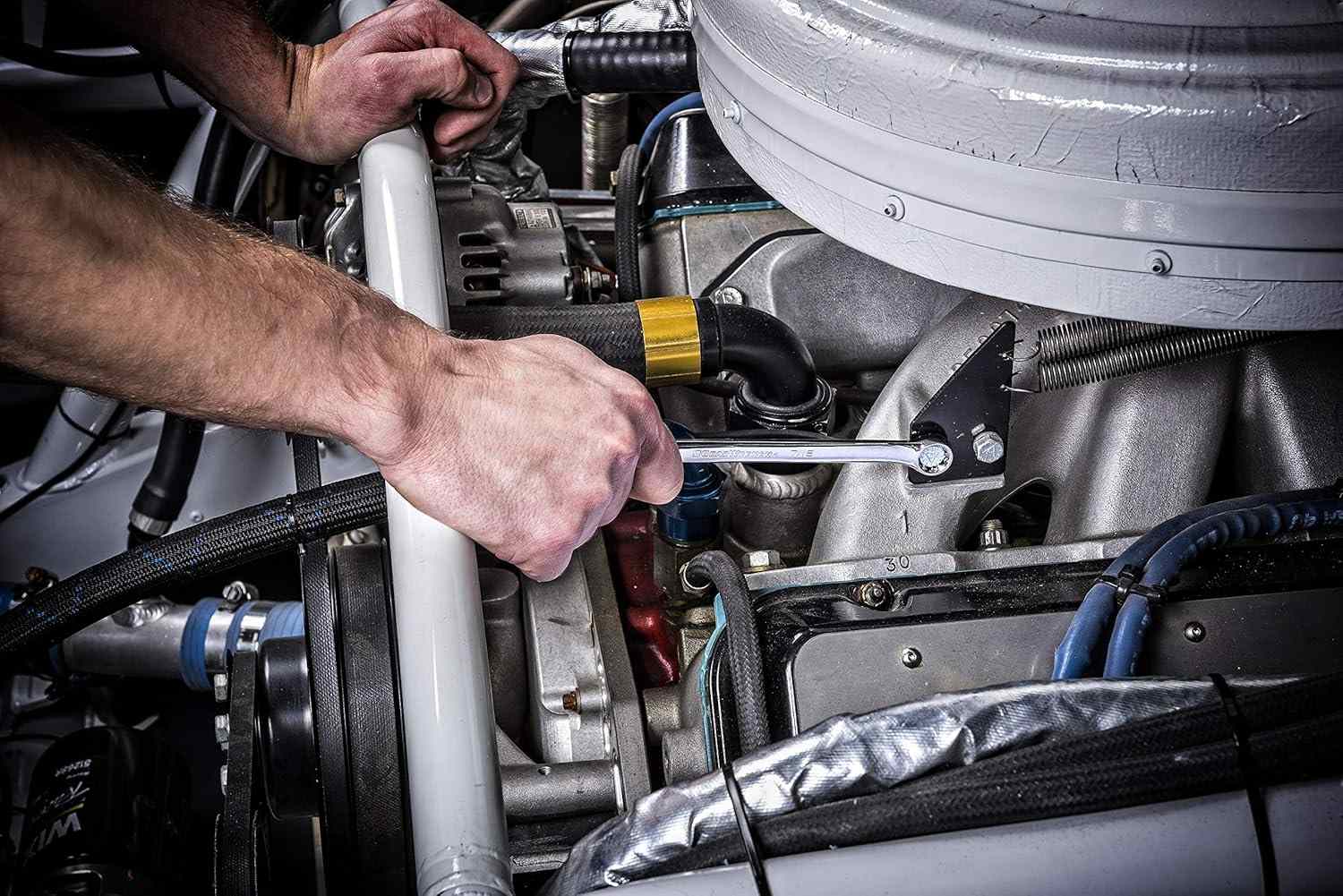 Action shot of a mechanic's hands using a GearWrench combination wrench to tighten a bolt within a vehicle engine bay.