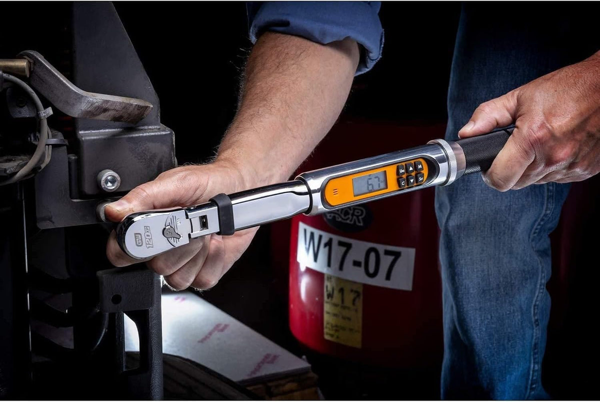 A close-up action shot of a mechanic's hands using the GEARWRENCH electronic torque wrench, with the digital display showing a reading.