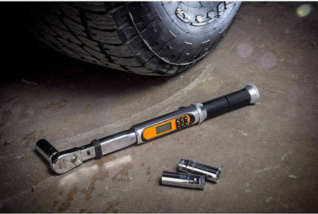 The GEARWRENCH 1/4-inch electronic torque wrench with a socket attached, resting on a concrete garage floor next to a tire.