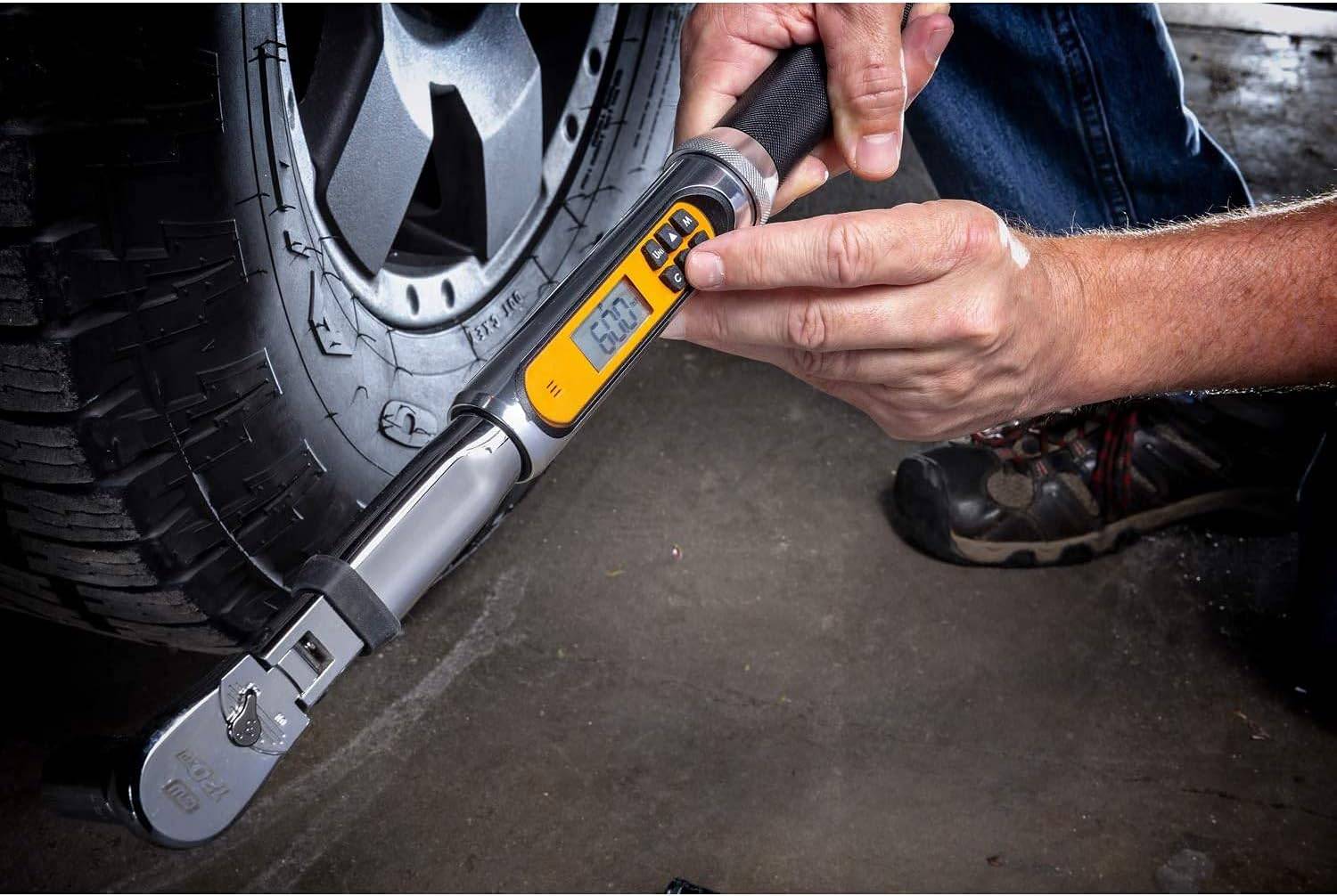 An action shot of a person's hands adjusting the settings on the digital display of the GEARWRENCH electronic torque wrench next to a car wheel.