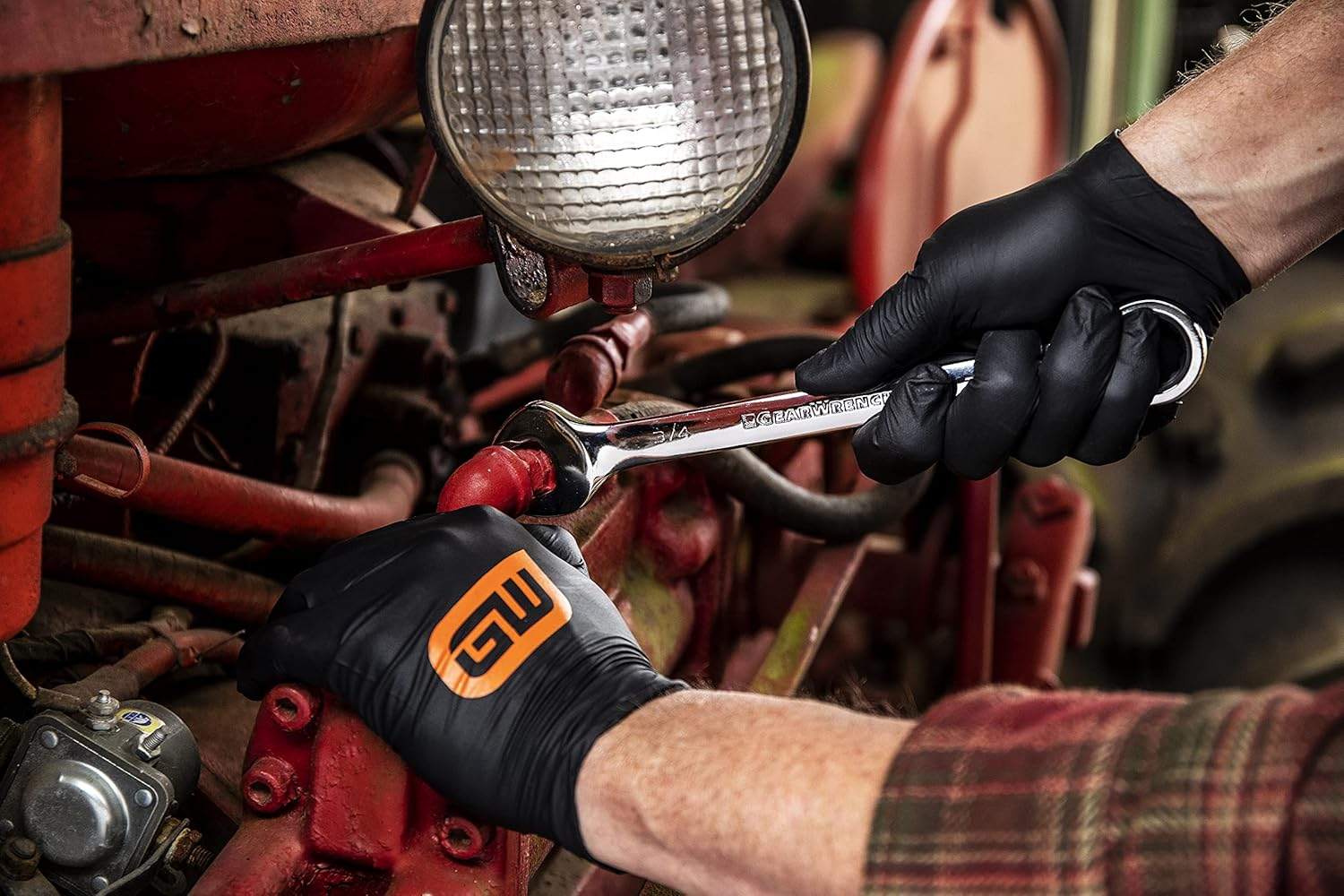 A user utilizing a GearWrench wrench on a tractor component, showing the versatility of the combination design in various mechanical applications.