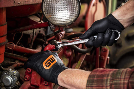 A user utilizing a GearWrench wrench on a tractor component, showing the versatility of the combination design in various mechanical applications.