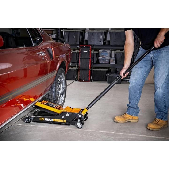 Gearwrench 1.5 Ton floor jack with yellow and black body; long handle and saddle positioned under vehicle.