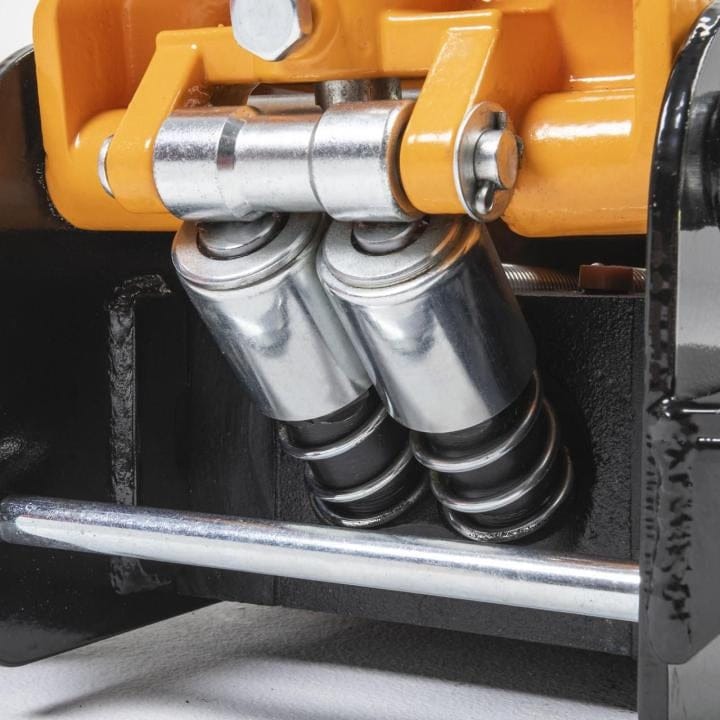 Close-up of dual piston system inside Gearwrench floor jack; black and orange frame with spring-loaded cylinders.