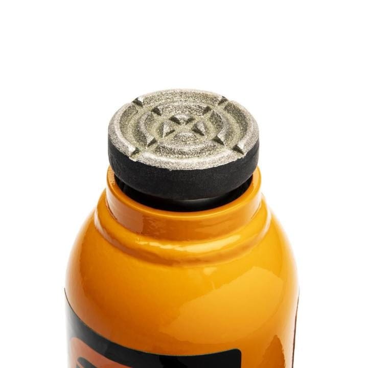 Top view of orange bottle with black metallic cap featuring star pattern; partial label visible on glossy surface.