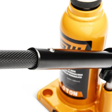 Close-up of PowerWrench 20 Ton hydraulic bottle jack with orange body and black handle; labeled lifting specs visible.